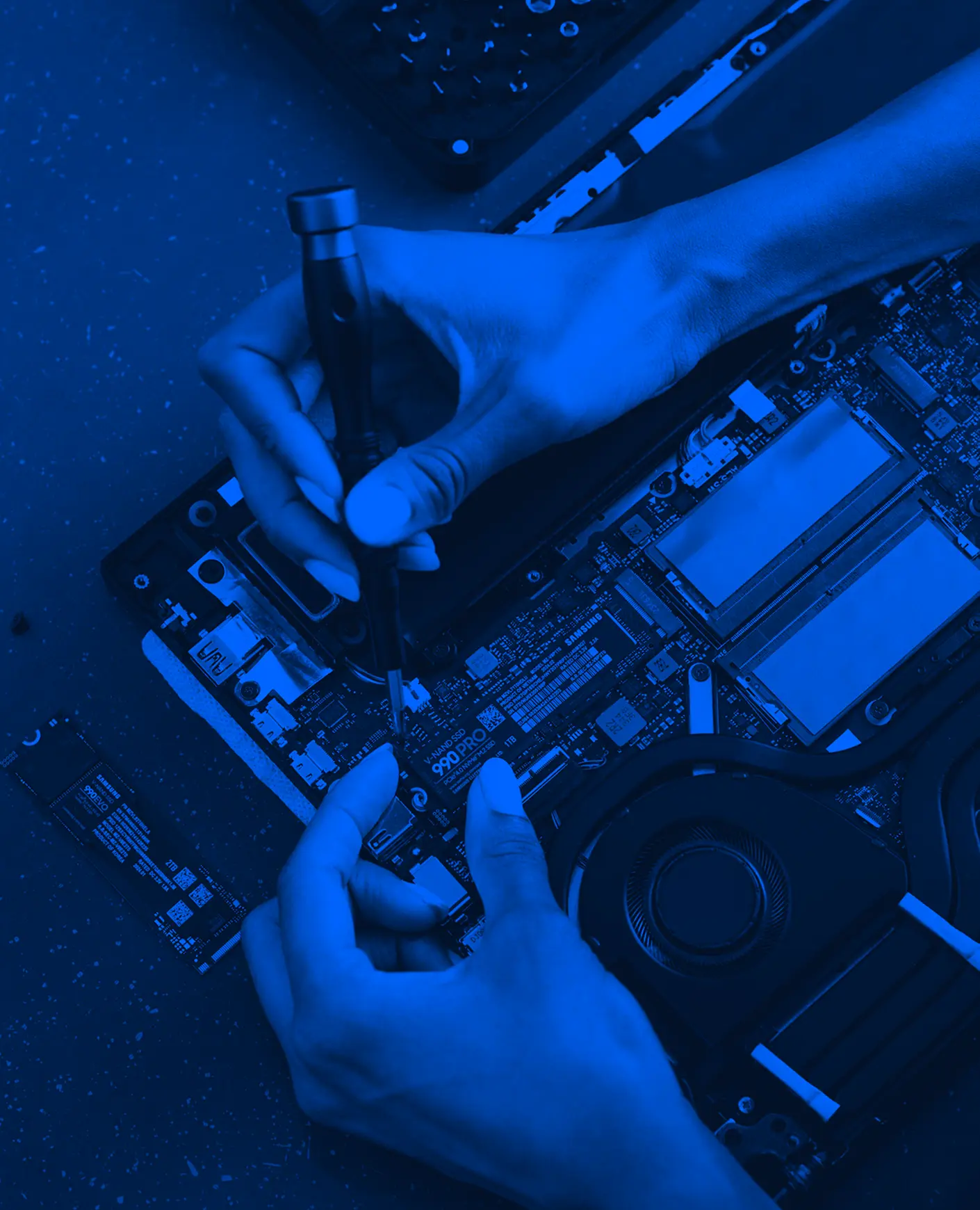 Uma pessoa consertando um laptop com uma chave de fenda.